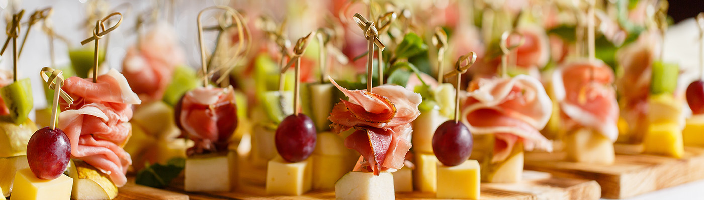 the buffet at the reception. Glasses of wine and champagne. Assortment of canapes on wooden board. Banquet service. catering food, snacks with cheese, jamon, prosciutto and fruit